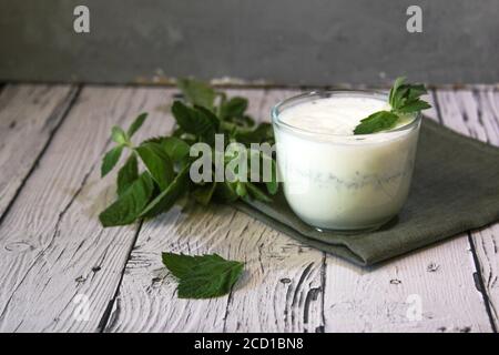 Milchshake mit Eis und Minze auf Holzhintergrund. Wählen Sie den Fokus auf die Tasse. Stockfoto