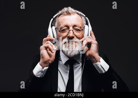 Studio isoliert Aufnahme von schönen reifen grauhaarigen Geschäftsmann mit Kopfhörern, lauschen Songs laut, entspannen und eine Pause für seine Seele. Peop Stockfoto