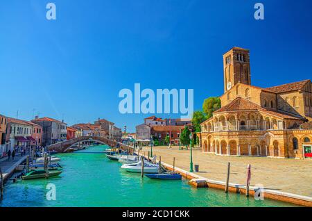 Stadtbild der Murano-Inseln mit Kirche Santa Maria e San Donato und Glockenturm Backsteingebäude, Brücke über den Wasserkanal mit Motorbooten, Region Venetien, Norditalien. Murano-Postkarte. Stockfoto