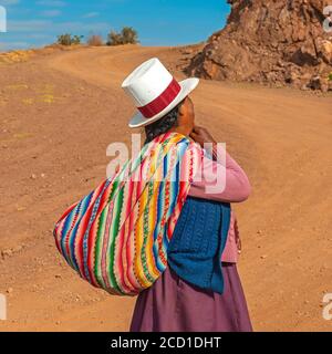 Indigene peruanische Quechua Frau mit traditionellen Hut und Textil entlang einer Andenstraße, Heilige Tal der Inka, Cusco, Peru. Stockfoto