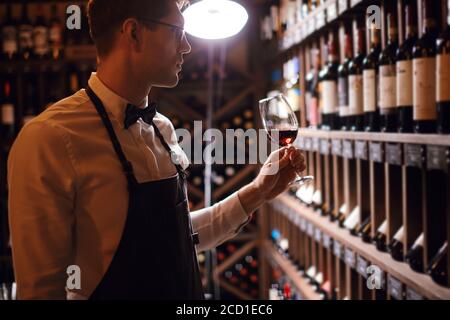 Cavist im Geschäft, Sommelier im Restaurant, Kritiker. Weindegustation. Verkostungserlebnis im Club, Mann hält ein Glas köstlichen Wein. Stockfoto