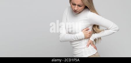 Junge nette kaukasische Frau mit Schmerzen, Muskel-oder chronischen Nervenschmerzen in ihrem Rücken nach der Arbeit. Erkrankungen der Wirbelsäule, Skoliose, Osteoporose Stockfoto