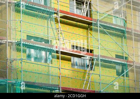 Gerüst und Sicherheitsnetz rund um das Haus zu installieren thermische Isolierung der Fassade des Mehrfamilienhauses Stockfoto