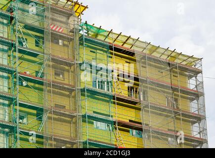 Gerüst und Sicherheitsnetz rund um das Haus zu installieren thermische Isolierung der Fassade des Mehrfamilienhauses Stockfoto