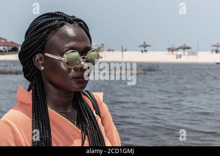 Afrika Frau mit Sonnenbrille aus Ghana genießen die Sonne an einem Strand in Accra. Stockfoto