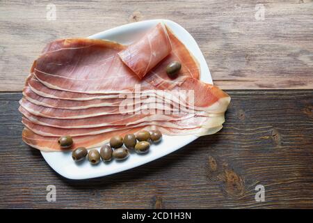 Balkan-Küche . Prsut-Scheiben: Trockengehäuteter Schinken, Balkan-Version von Prosciutto. Rustikaler Hintergrund. Speicherplatz kopieren Stockfoto