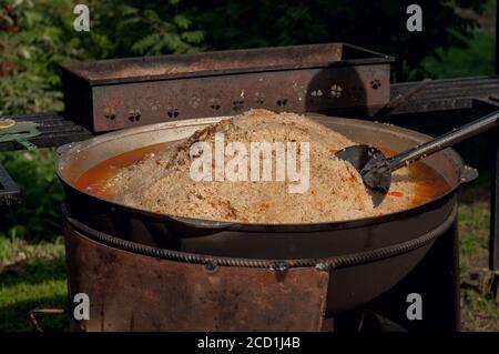 Nationale Nahrung der östlichen Völker. Pilaf in einem großen Kessel. Reis und Lamm über dem Feuer gekocht. Kochen von nationalen Speisen Stockfoto