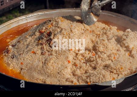 Nationale Nahrung der östlichen Völker. Pilaf in einem großen Kessel. Reis und Lamm über dem Feuer gekocht. Kochen von nationalen Speisen Stockfoto