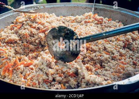 Nationale Nahrung der östlichen Völker. Pilaf in einem großen Kessel. Reis und Lamm über dem Feuer gekocht. Kochen von nationalen Speisen Stockfoto