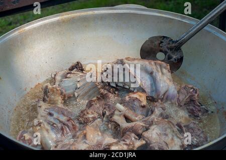 Usbekischer Pilaf wird gekocht. Nationale Küche. Braten von Fleisch in einem großen Kessel Stockfoto