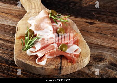 Italienischer Prosciutto crudo oder Jamon mit Rosmarin. Vorspeise aus rohem Schinken Stockfoto