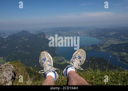 Wanderer, der auf einem Berggipfel mit Blick auf den Wolfgangsee in Strobl, Österreich, ruht Stockfoto