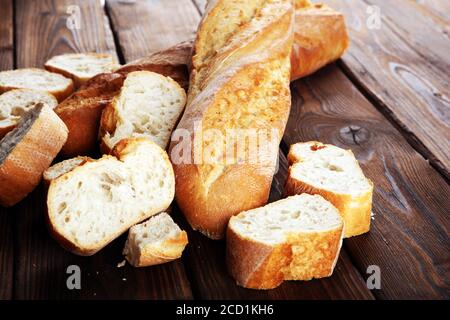 Baguette gebackenes Brot und geschnittenes Baguette auf Holzhintergrund Stockfoto