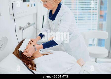 Sorgfältige Ärztin Sorgen um ihre junge Patientin, kümmern sich um sie, während sie auf dem Bett liegen. Arzt in weißer Uniform, Bademantel isoliert in Hospi Stockfoto