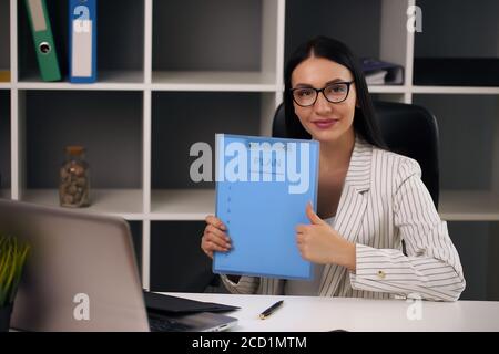 Porträt des Lächelns hübsche junge Geschäftsfrau in Gläsern sitzen am Arbeitsplatz Stockfoto