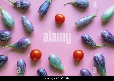 Lila Auberginen und rote Tomaten auf rosa Papier. Speicherplatz kopieren Stockfoto