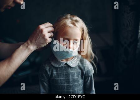 Eltern helfen Tochter Dressing Uniform und legen Gesichtsmaske Vorbereitung Zurück zur Schule Stockfoto