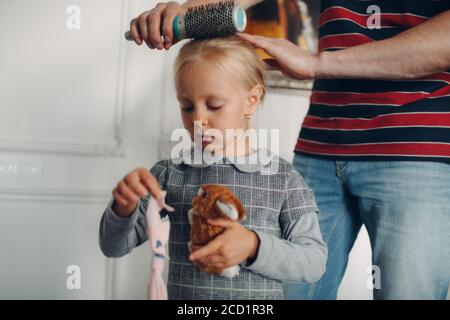 Vater Kämme und helfen Tochter Dressing Uniform Vorbereitung zurück in die Schule. Stockfoto