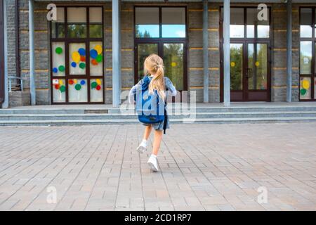 Nettes kleines Mädchen mit Rucksack läuft zurück zur Schule Stockfoto