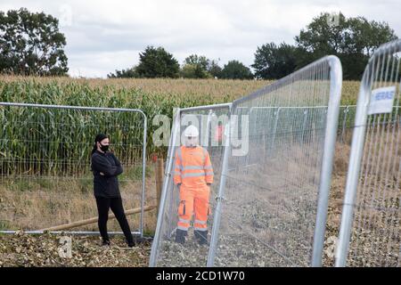 Offchurch, Großbritannien. August 2020. Ein HS2-Arbeiter überwacht einen Anti-HS2-Aktivist während der Baumfällarbeiten neben dem Fosse Way in Verbindung mit der HS2-Hochgeschwindigkeitsbahnverbindung. Das umstrittene HS2-Infrastrukturprojekt wird derzeit £106 Mrd. kosten und viele unersetzliche natürliche Lebensräume zerstören oder erheblich beeinflussen, darunter 108 alte Waldgebiete. Kredit: Mark Kerrison/Alamy Live Nachrichten Stockfoto