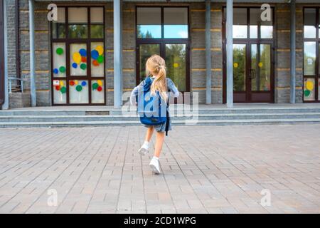 Nettes kleines Mädchen mit Rucksack läuft zurück zur Schule Stockfoto