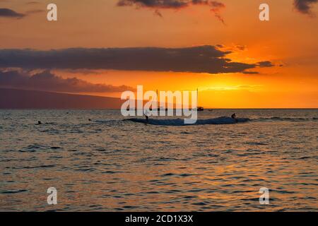 Sonnenuntergang am Lahaina Hafen auf Maui, mit silhouetted Surfern. Stockfoto