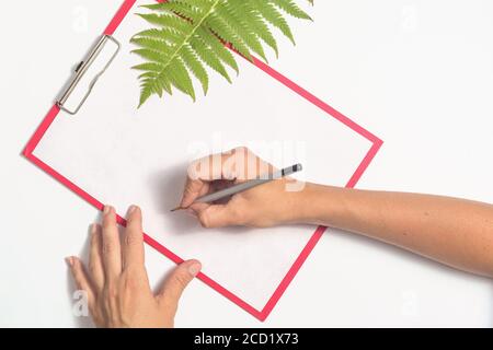Weibliche Hände schreiben auf einem weißen Blatt Papier Stockfoto