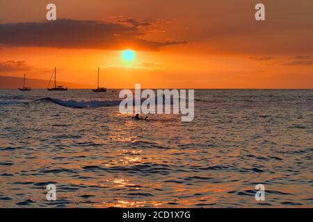 Blick auf den Hafen von Lahaina auf Maui mit seinen silhouettierten Surfern. Stockfoto