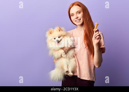 Charming gut aussehende Frau in stilvollen Freizeitkleidung Kontrolle der Nahrung ihres Haustiers, richtige Ernährung Ration, Ernährung. Copy space, isoliert blauen Hintergrund, Stockfoto