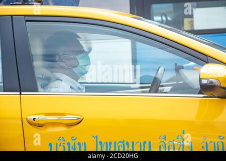 BANGKOK, THAILAND, JULI 05 2020, der Fahrer fährt ein Taxi mit einer Schutzmaske auf seinem Gesicht. Stockfoto