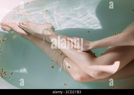 Cropped weibliche Besitzerin von schlanken langen Beinen mit weißer, braungebrannter Haut, die während einer Spa-Behandlung im Wellness-Bereich des Hotels baden. Stockfoto