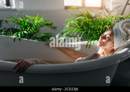 Attraktive rothaarige junge Touristen entspannen sich in der Badewanne des Hotel Spa und genießen die Ruhe, die harmonische Design-Elemente mit premi kombiniert Stockfoto