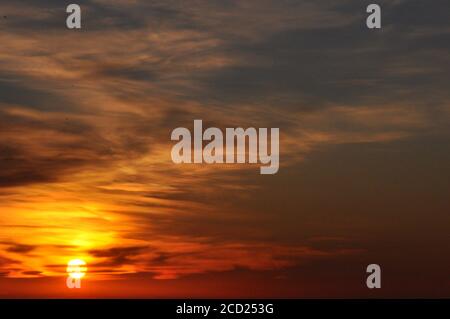 Wunderschöner Hintergrund am Sonnenuntergang mit Wolken, die die Sonne verbergen Stockfoto
