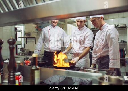 Feuer in der Küche. Feuergasbrand ist Kochen auf Eisenpfanne, rühren Feuer sehr heiß Stockfoto