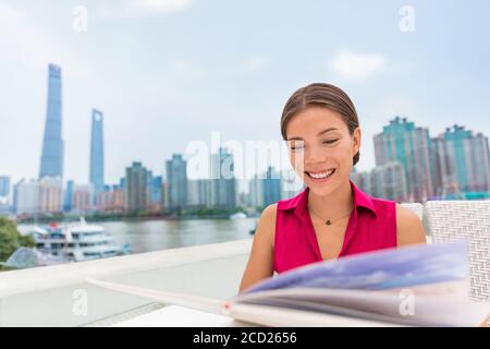 Asiatische Frau essen im Shanghai Waterfront Outdoor Restaurant mit Blick auf Menü Auswahl Mahlzeit zum Abendessen. Chinesische Mädchen essen lokale Speisen im Bund Stockfoto