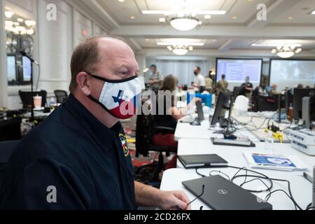 Austin, Texas, USA. August 2020. Ein Staatsbeamter arbeitet mit einer texanischen Gesichtsmaske, während Gouverneur Greg Abbott (nicht gezeigt) die Presse über die Vorbereitungen von Texas auf den Hurrikan Laura informiert, der am Donnerstag im Osten von Texas und an der Küste von Louisiana landen soll. Abbott mobilisierte Hunderte von staatlichen Ressourcen, da Texaner sich an die extremen Schäden erinnern, die der Hurrikan Harvey 2017 angerichtet hatte. Quelle: Bob Daemmrich/ZUMA Wire/Alamy Live News Stockfoto