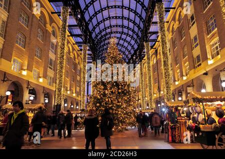 Festliche Lichter, Marktstände und ein wunderschön dekorierter Weihnachtsbaum unter dem Gewölbedach in Hay's Galleria, London, England, Großbritannien Stockfoto