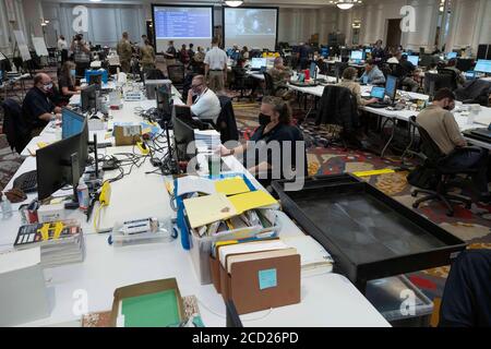 Austin, Texas, USA. August 2020. Texanische Beamte sammeln Daten im staatlichen Emergency Operations Center (EEOC) in einem lokalen Hotel, da Gouverneur Greg Abbott (nicht gezeigt) die Presse über die Vorbereitungen von Texas auf den Hurrikan Laura informiert, der am Donnerstag im Osten von Texas und an der Küste von Louisiana landen soll. Abbott mobilisierte Hunderte von staatlichen Ressourcen, da Texaner sich an die extremen Schäden erinnern, die der Hurrikan Harvey 2017 angerichtet hatte. Quelle: Bob Daemmrich/ZUMA Wire/Alamy Live News Stockfoto