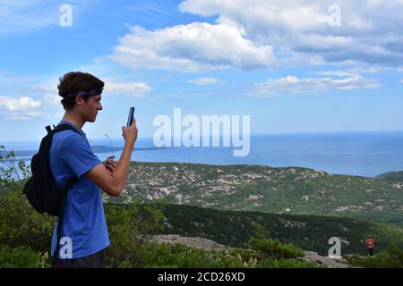 Junger Mann, der mit seinem Handy fotografiert Spitze eines Berges Stockfoto