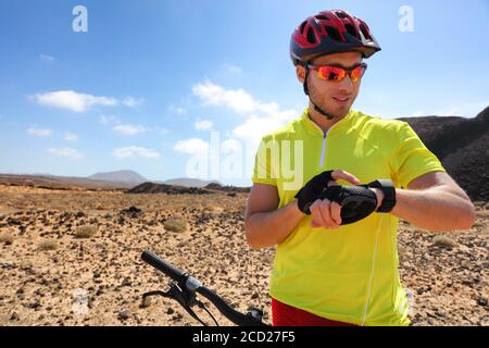 Sport Fitness Uhr Mountainbiker auf mtb-Bike mit Smartwatch App für Fitness Challenge. Junger Mann Athlet mit seinem tragbaren Tech-Radfahren in Stockfoto