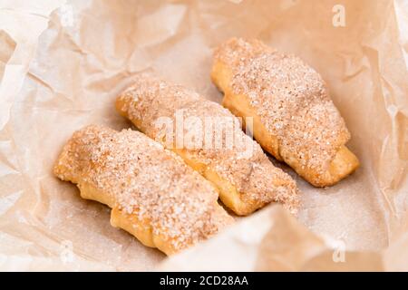 Frische Croissants mit Zimt auf faltenem Papier auf Holzhintergrund Tabelle Stockfoto