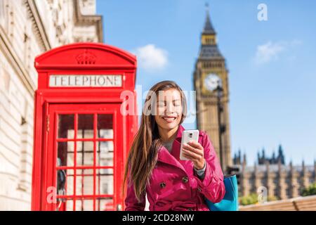 London Handy Geschäftsfrau zu Fuß in der Stadt in stilvollen rosa Trenchcoat, städtischen Lebensstil. Rote Telefonzelle und Big Ben Hintergrund London Stockfoto