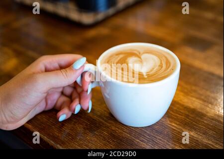 Frau hält eine Tasse Kaffee mit Schaum. Cappuccino Stockfoto