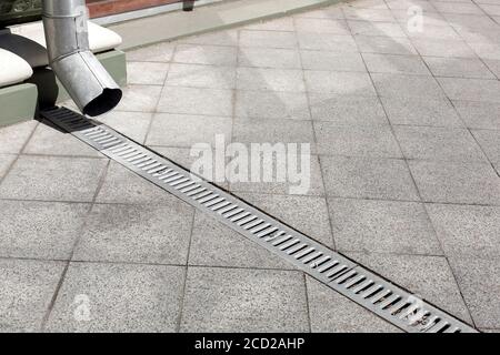 Galvanisierte Downauslauf auf Fassade Gebäude mit Eisen Drainage Rost aus grauem Stein Granit Bürgersteig aus quadratischen Fliesen auf dem Boden, Nahaufnahme Details Stadt infr Stockfoto