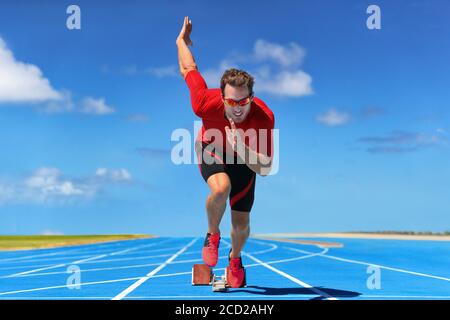 Laufsportler beginnt am Start der Laufstrecke auf blauen Laufstrecken bei der Leichtathletik im Freien und im Stadion Fiel. Sprinter im Rennen. Sport und Stockfoto