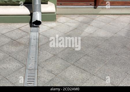 Engineering-Struktur downspout auf Fassade Gebäude mit Entwässerungsgitter aus grauem Stein Granit Gehweg aus quadratischen Fliesen auf dem Boden mit Kopierraum, clos Stockfoto