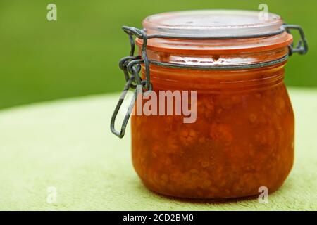 Ein Glas mit Moltebeermarmelade auf grünem Hintergrund Stockfoto