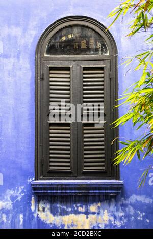 Vertikale Aufnahme eines Vintage-Fensters an einer lila Wand Stockfoto