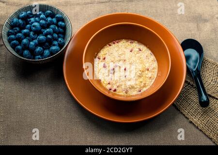 Haferflocken mit verschiedenen Beeren. Gesundes Frühstück Stahl geschnitten Haferbrei Haferbrei mit Heidelbeere Brombeere. Haferbrei und Heidelbeeren Stockfoto