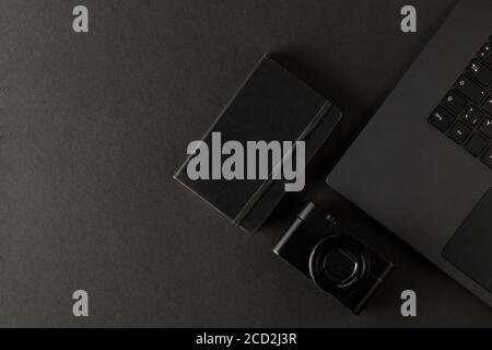 Digitalkamera und Notebook neben Laptop auf schwarzem Schreibtisch im Büro, Digitalfotografie oder Bildverarbeitungskonzept, Draufsicht flach liegend von oben mit Stockfoto